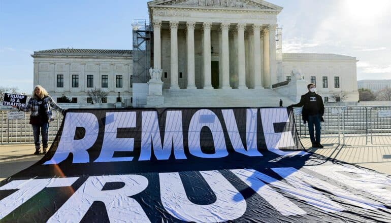 Protesters outside the Supreme Court hold a large sign that reads "Remove Trump."