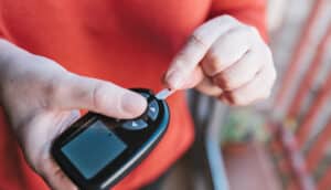 A woman uses a blood glucose meter.