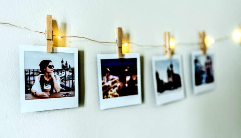 Several polaroid pictures hanging on a string of lights on a wall.