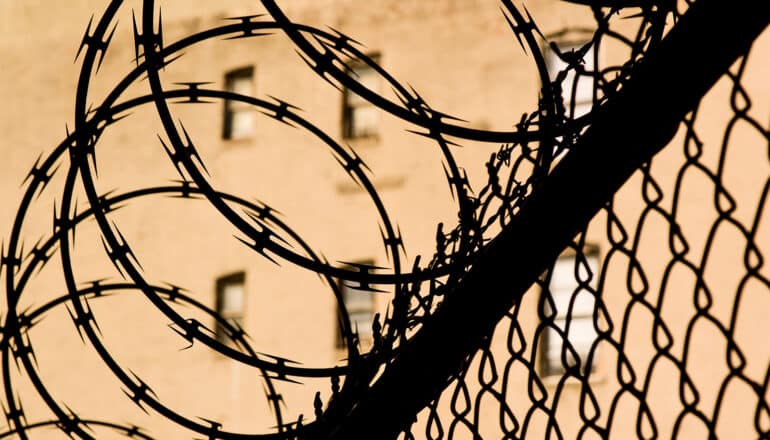 A barbed wire fence outside a prison building.