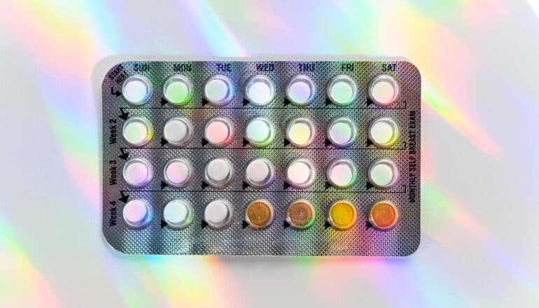 A package of birth control pills with colorful light cast on them.