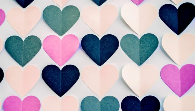 Rows of hearts cut out of colorful paper.