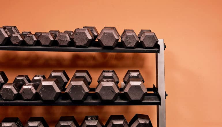 Racks of weights in an orange room.