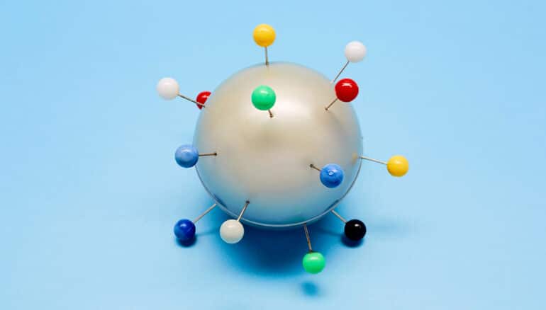 A ball with push pins stuck in it made to look like the virus that causes Covid-19.