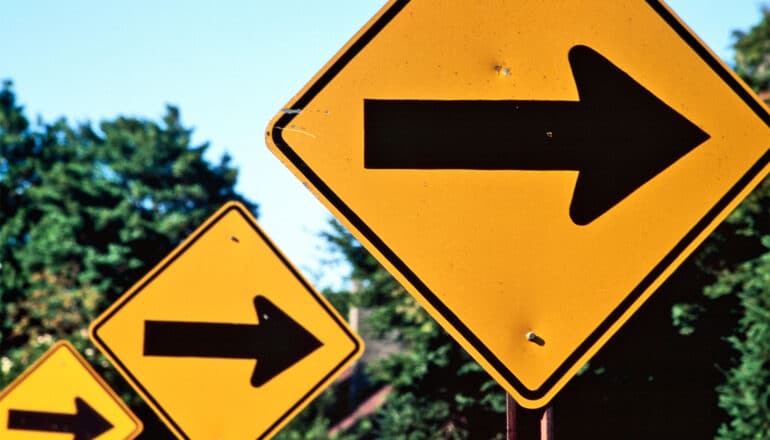 Yellow road signs have right-pointing arrows on them.