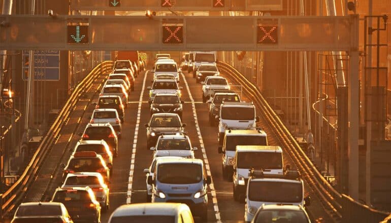 Cars fill a bridge during a hazy sunset.