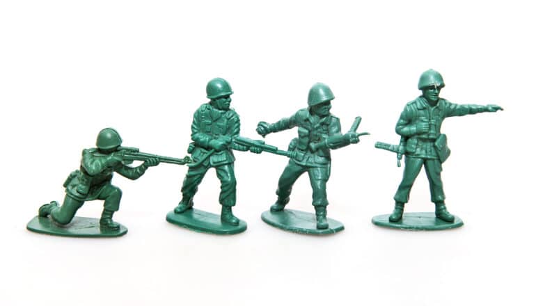 Four green army men toys on a white background.