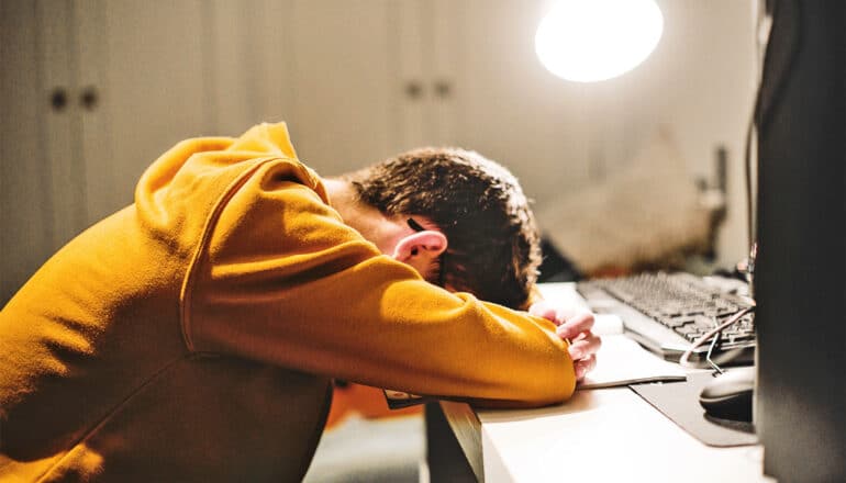 A college student has his head on his desk.