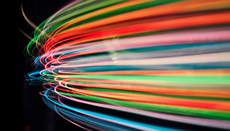 Colorful beams of light curve together on a black background.