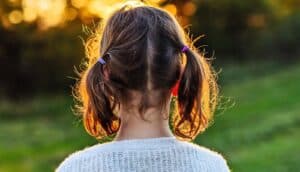 A young girl watches a sunset outside.