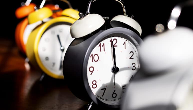 A row of retro alarm clocks sit on a table.