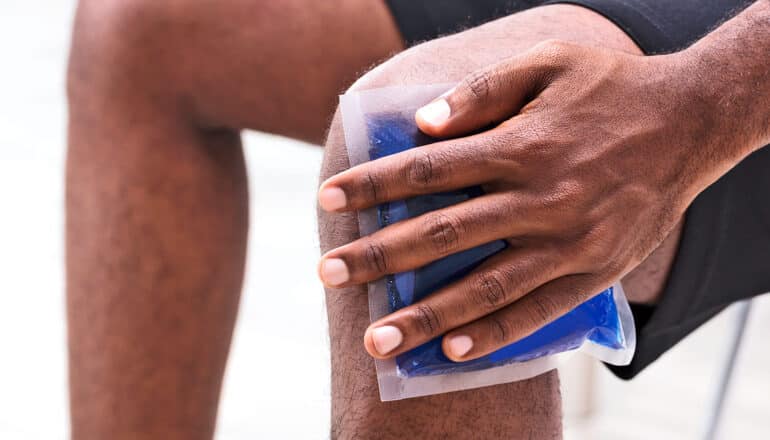 A man puts an ice pack on his knee.