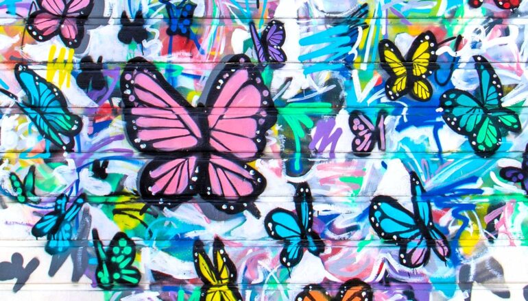 Graffiti of colorful butterflies on a white wall.