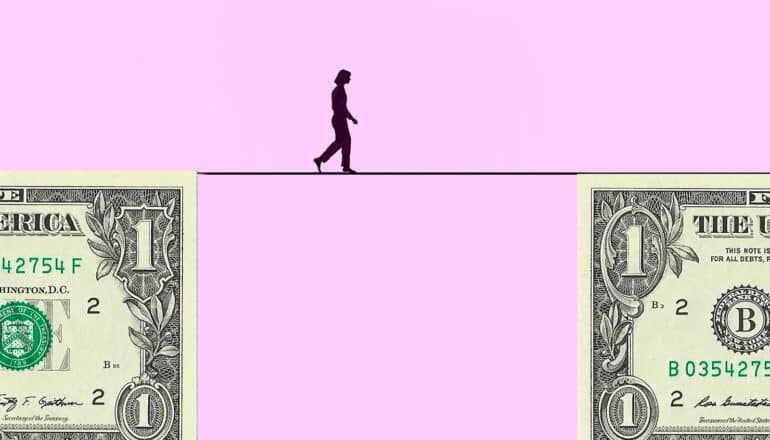 A person walks across a line connecting two dollar bills.