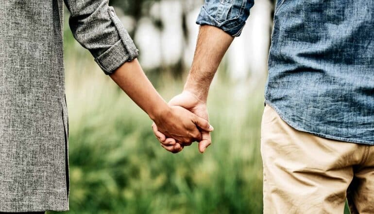 A couple holding hands while walking outside.