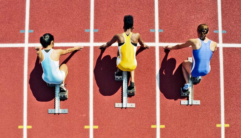 Three runners line up at the starting line before a track race.