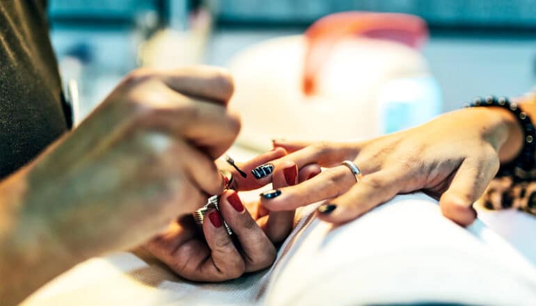 A woman at the nail salon is getting her nails painted.