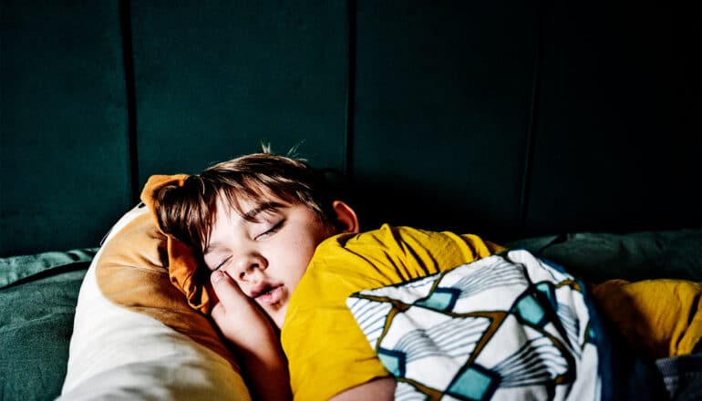 A young boy sleeps with his hand under his face.