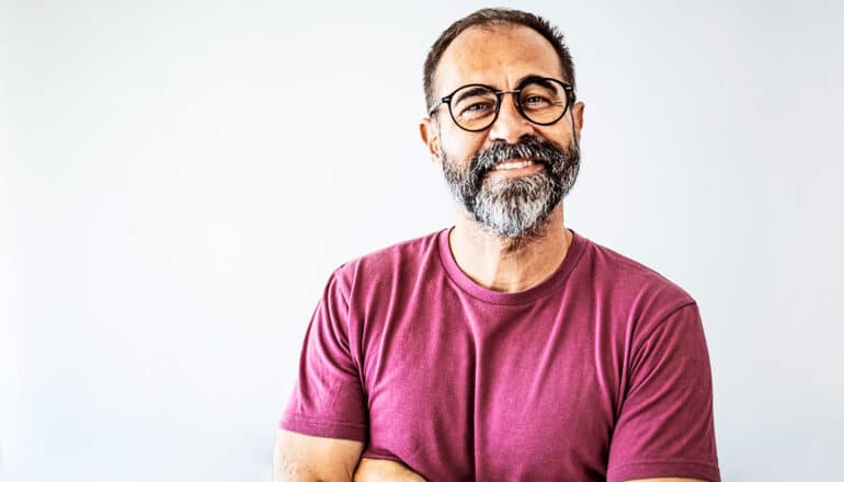 A smiling middle-age man wearing glasses looks at the camera.