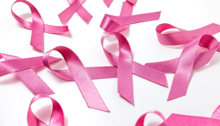 Several pink ribbons sit on a white surface.