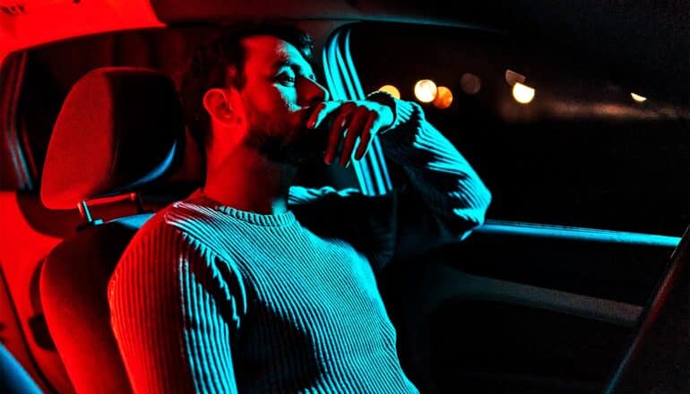 A man looks tired while behind the wheel of a car.