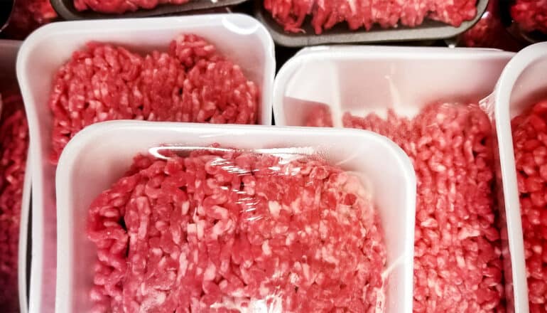 Packages of pink ground beef at a supermarket.