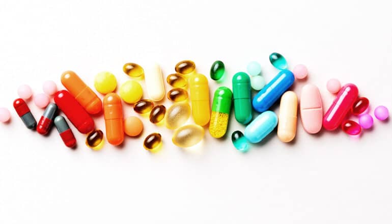 Many colorful pills arranged by color on a white background.