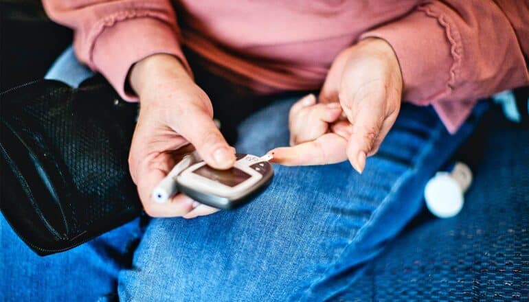 A woman with diabetes checks her blood sugar with a pinprick device.