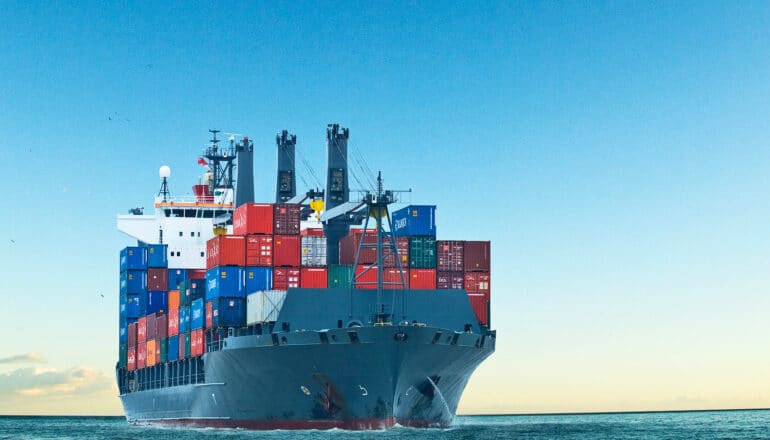 A cargo ship hauls colorful shipping containers while on the water.