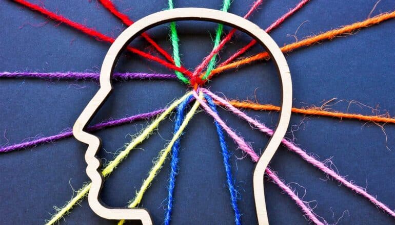 Colorful string leads into the outline of a human head where all the strands are tangled together.