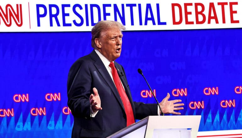 Former President Donald Trump speaks into a microphone at a podium during a presidential debate.