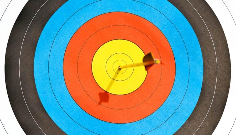 An arrow lodged in the very center of an archery target.