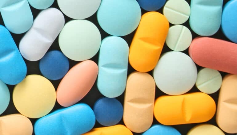 Many colorful pills on a black background.