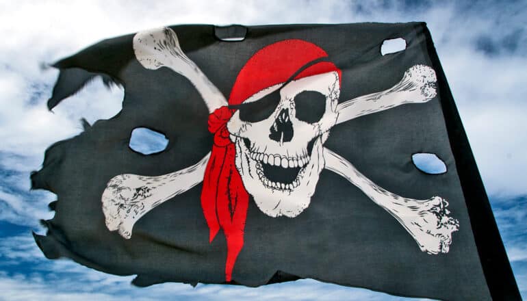 A black flag has a skull and crossbones symbol on it, with the skull wearing a red bandana and eyepatch.