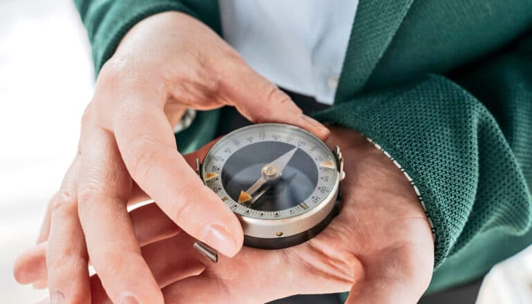 A person holds a compass in one palm.