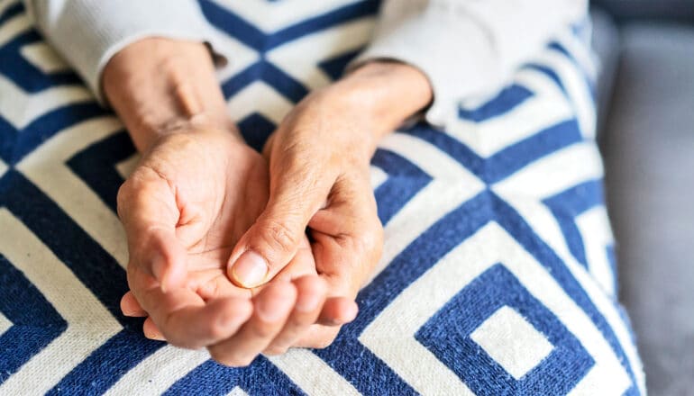 An older woman massages one hand with the other.