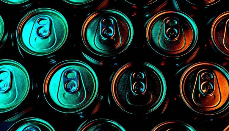 Rows of aluminum cans illuminated in green light in the dark.