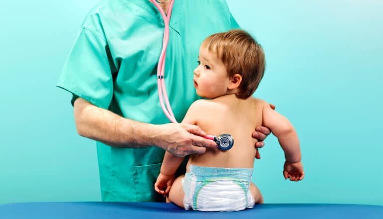 A doctor uses a stethoscope to listen to a baby's breathing.