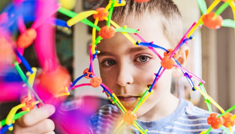 A young boy looks through an expandable plastic sphere toy.