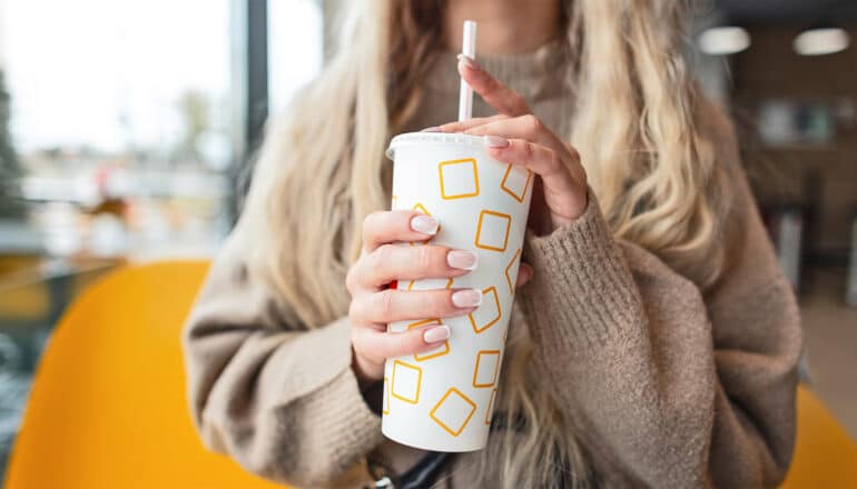 A young woman holds a cup of soda.