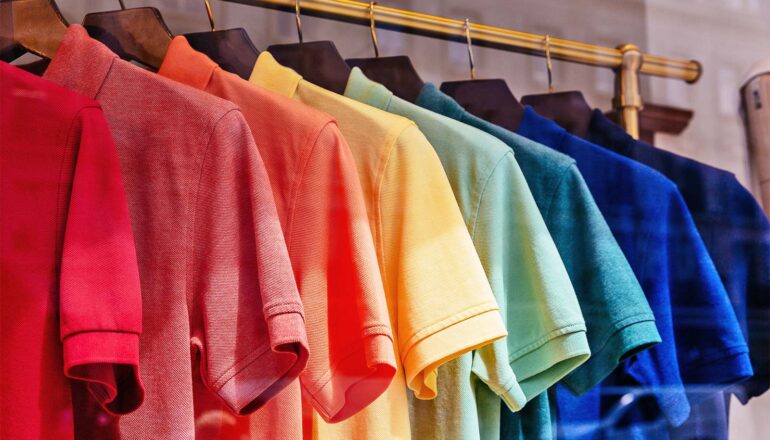 A clothing rack with many colorful polo shirts of the same type hanging.