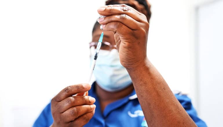 A health care worker fills a syringe with the Covid-19 booster.