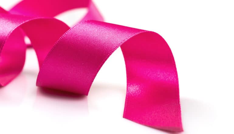 A pink ribbon unfurls on a white surface.