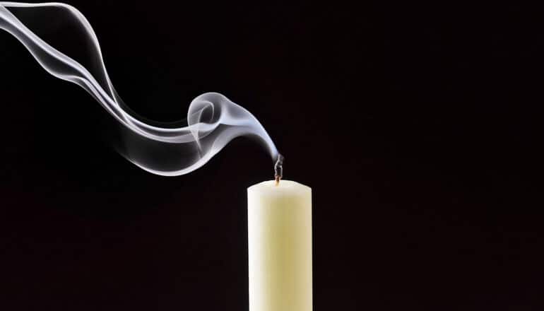 A candle is extinguished and has smoke coming off its wick.