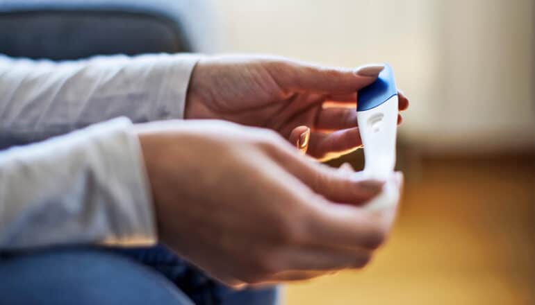 A woman holds a pregnancy test while waiting for the result.