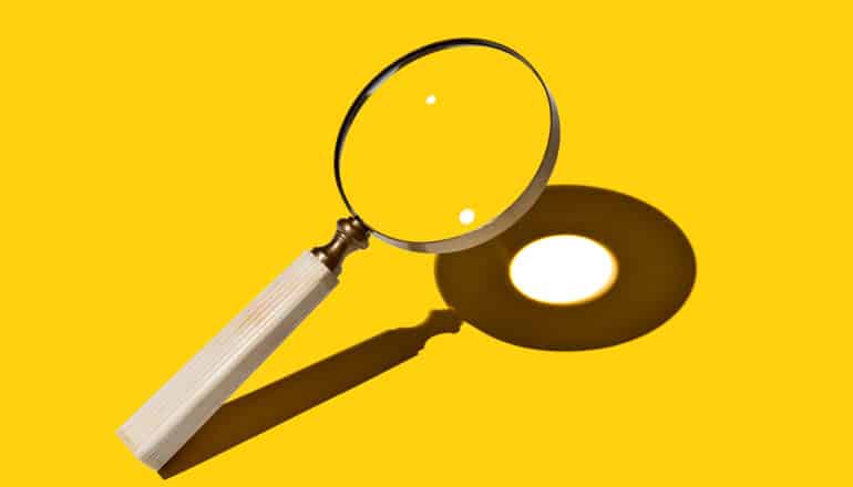 A magnifying glass shines a light on a yellow surface.