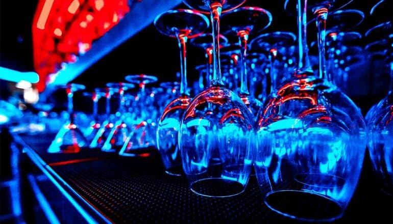 Rows of overturned empty wine and cocktail glasses at a bar.