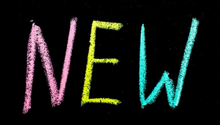 The word "new" written on a chalkboard in pink, yellow, and blue.