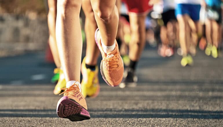 Marathon runners run on an asphalt road.