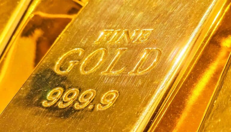 A gold bar has the words 'Fine Gold' stamped on it above the number 999.9.